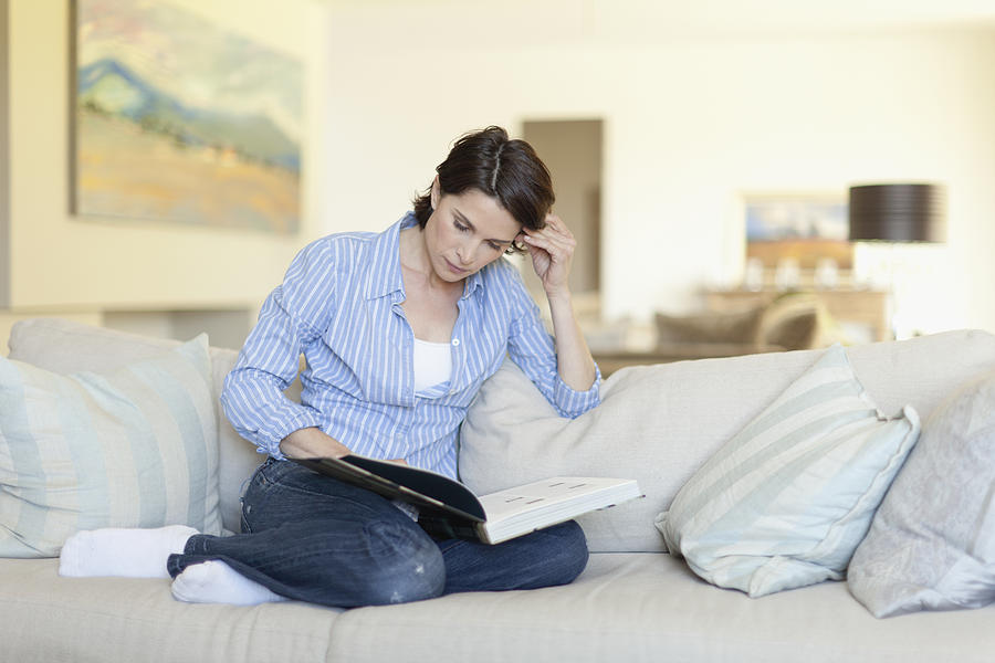 Woman reading on couch Photograph by Hybrid Images