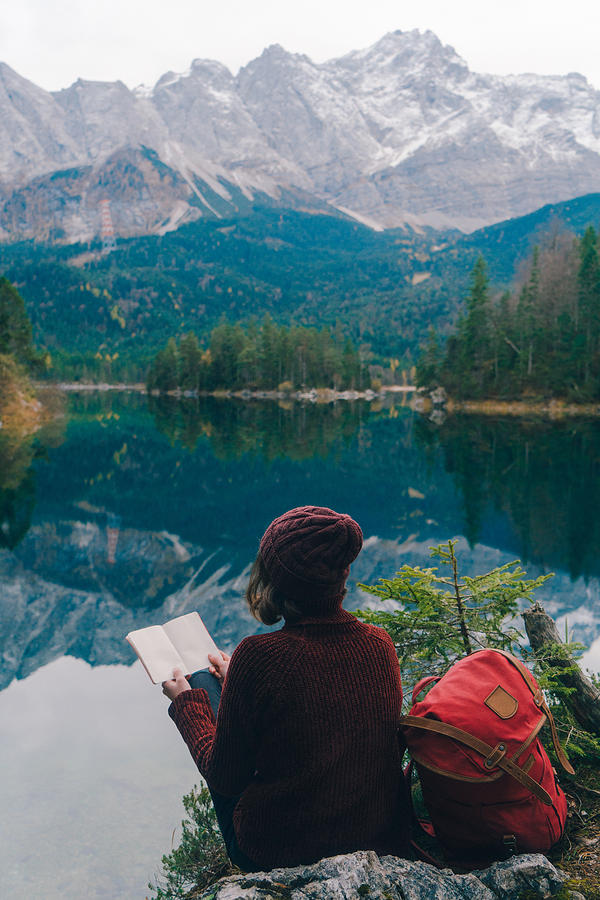 Woman reading on the background of  scenic view of Eibsee lake in Alps Photograph by Oleh_Slobodeniuk