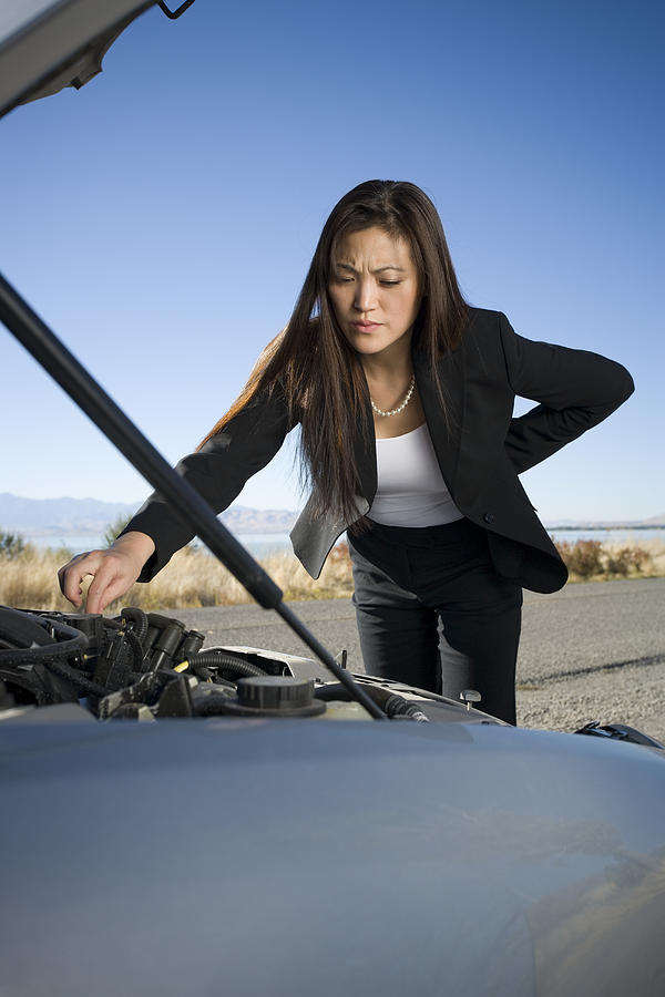 Woman repairing checking her car engine Photograph by Rubberball
