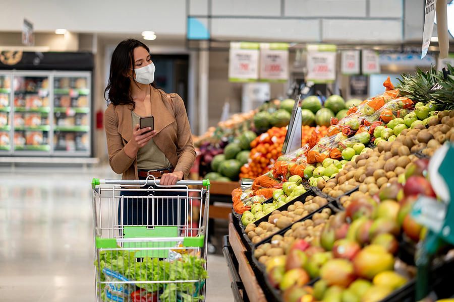 Woman shopping at the grocery store wearing a facemask Photograph by Hispanolistic