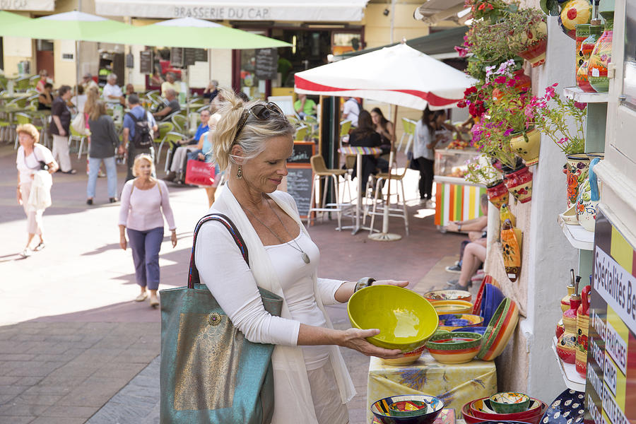 Woman shops for pottery in outdoor market Photograph by Ascent/PKS Media Inc.