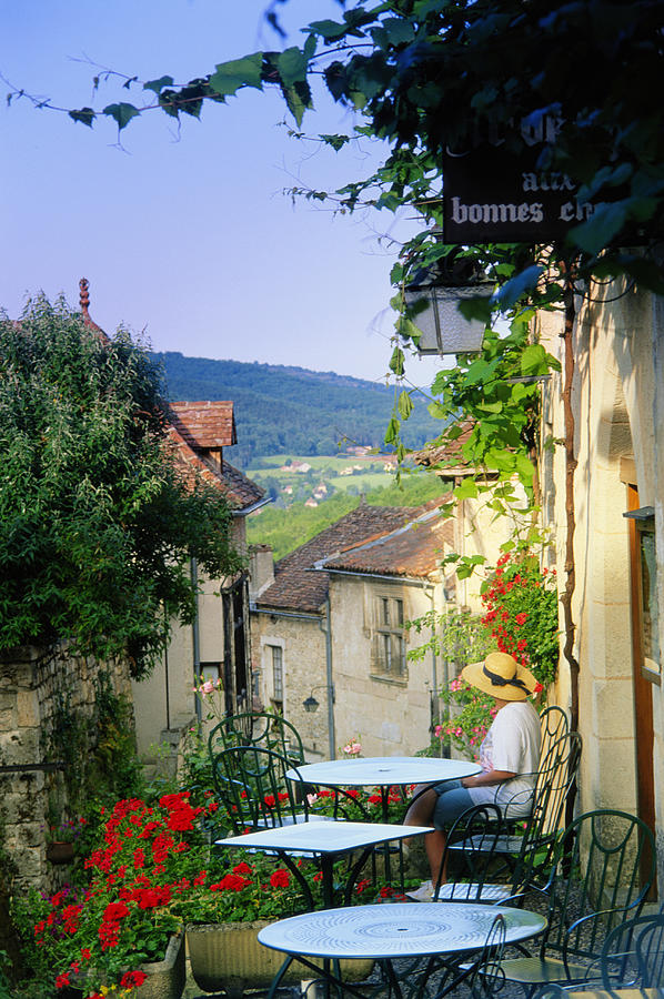Woman sitting at outdoor cafe overlooking village, elevated view Photograph by Peter Adams