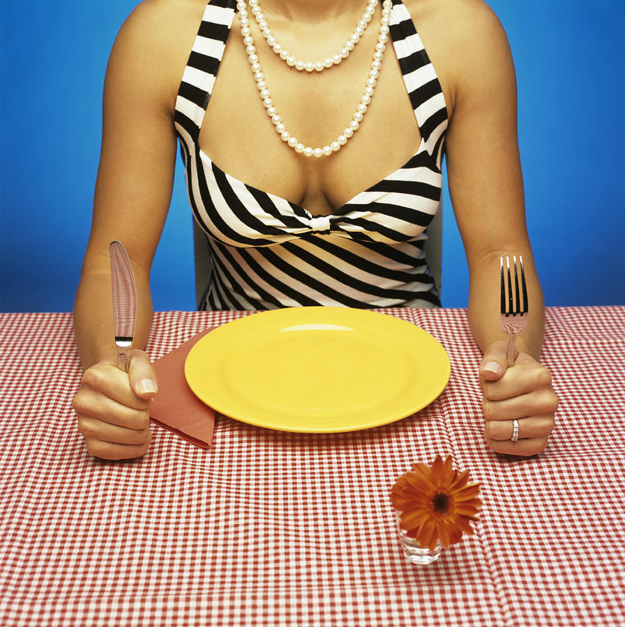Woman sitting at table with empty plate, holding cutlery Photograph by Jacob Lindner