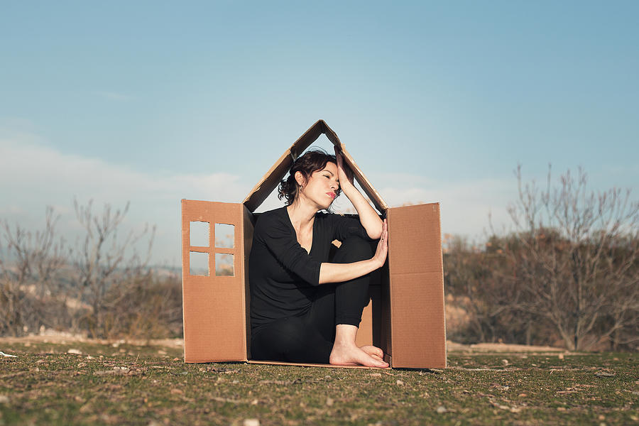 Woman sitting in cardboard box house Photograph by Elenaval