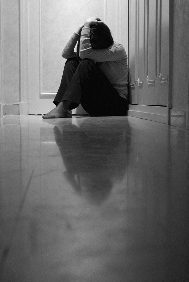 Woman sitting in corridor with head in hands, ground view (B&W) Photograph by Sami Sarkis