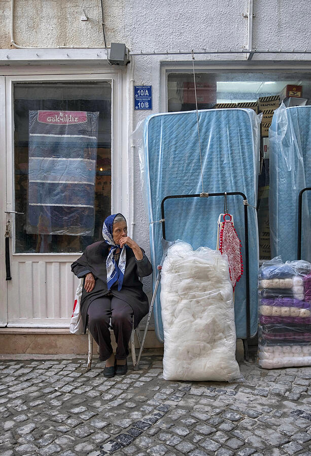 woman sitting in front of her shop in Alacati. Photograph by Emreturanphoto