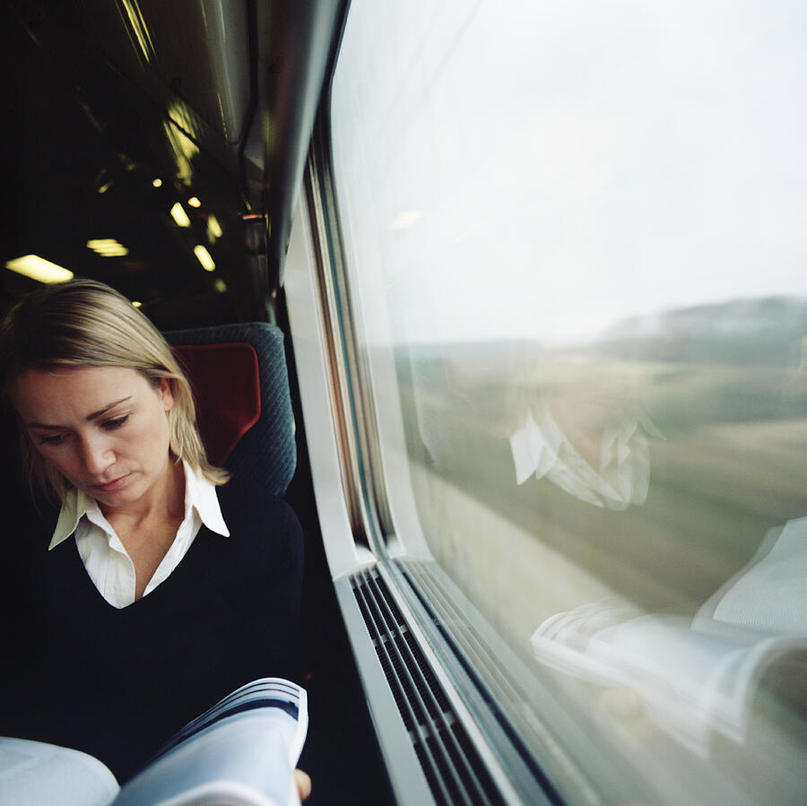 Woman sitting in train, reading magazine Photograph by STasker