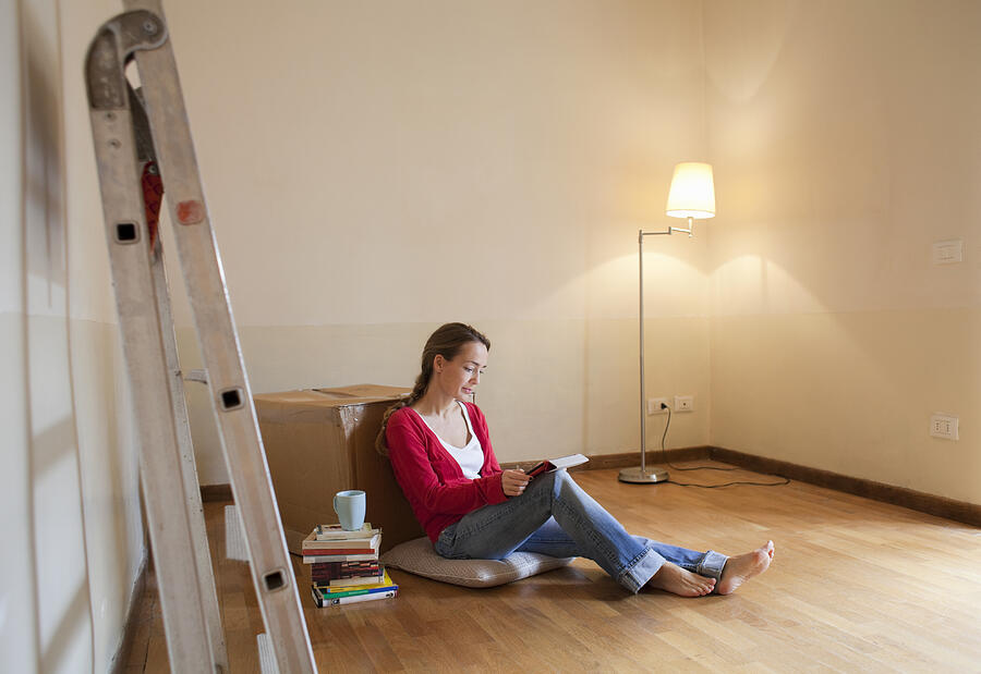 Woman Sitting On Floor Of Her New, Empty Apartment Photograph by Kathrin Ziegler