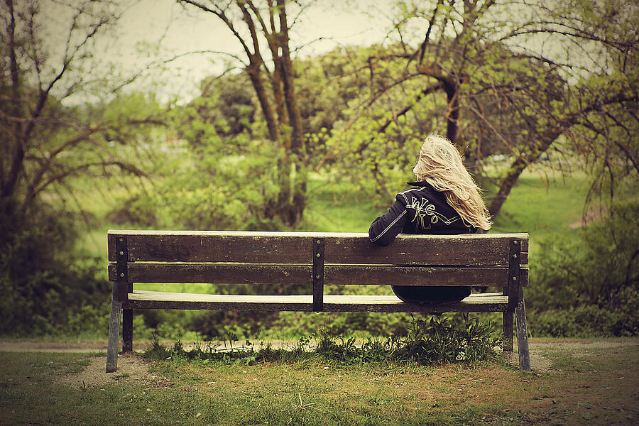 Woman sitting on wooden bench. Photograph by Carmen Hache fotografía