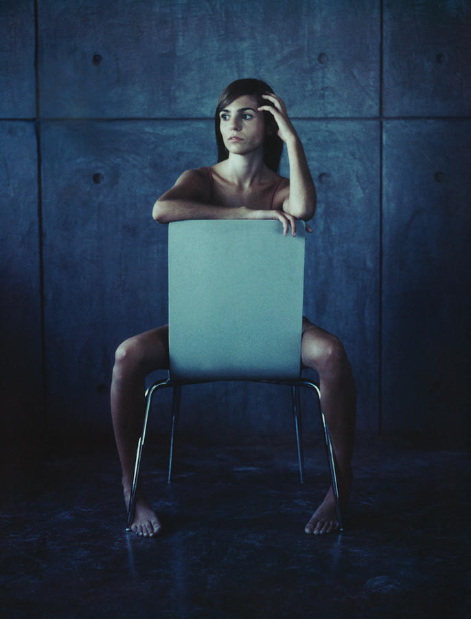 Woman sitting straddled, hand to head. Photograph by Matthieu Spohn