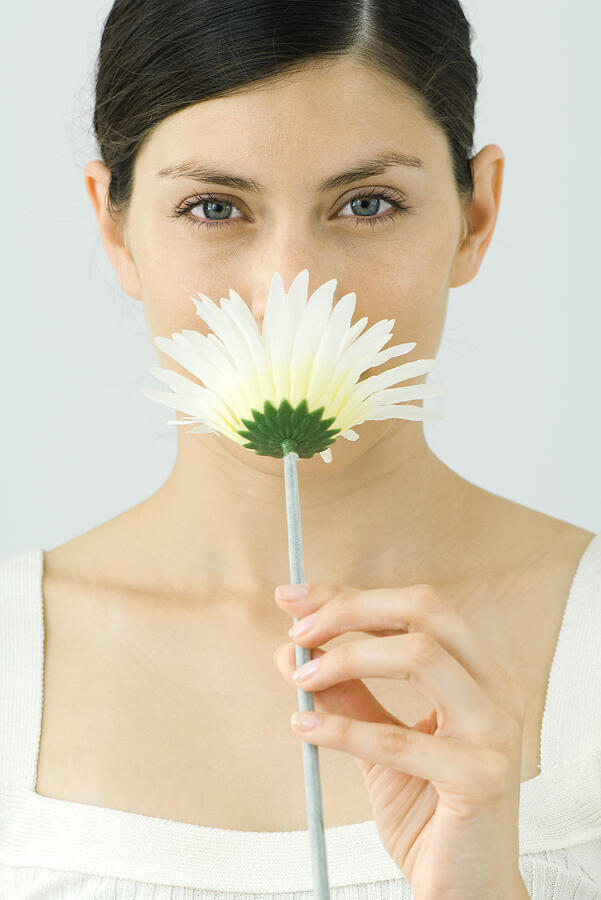 Woman smelling flower, looking at camera, portrait Photograph by ZenShui/Milena Boniek