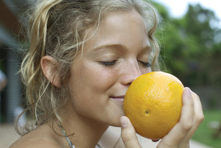 Woman smelling fresh orange Photograph by PhotoAlto/Antoine Arraou