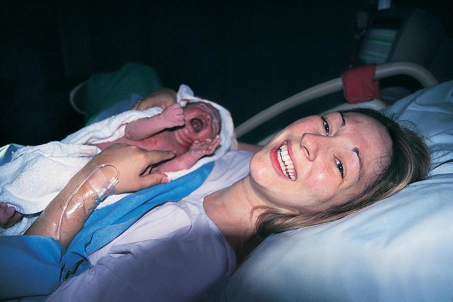 Woman Smiling Holding Her Newborn Baby Photograph by Digital Vision.