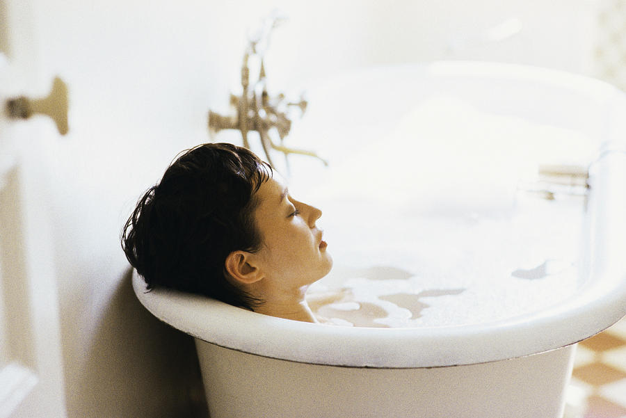 Woman soaking in bubble bath Photograph by PhotoAlto/John Dowland