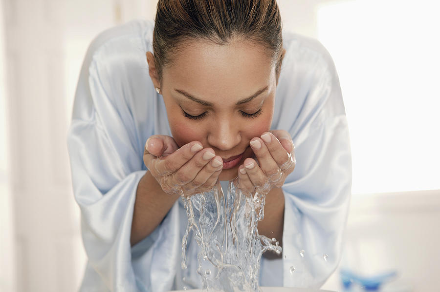 Woman splashing water on face Photograph by Comstock Images