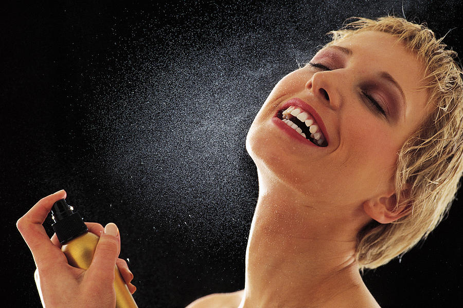 Woman spraying perfume on her neck Photograph by Comstock