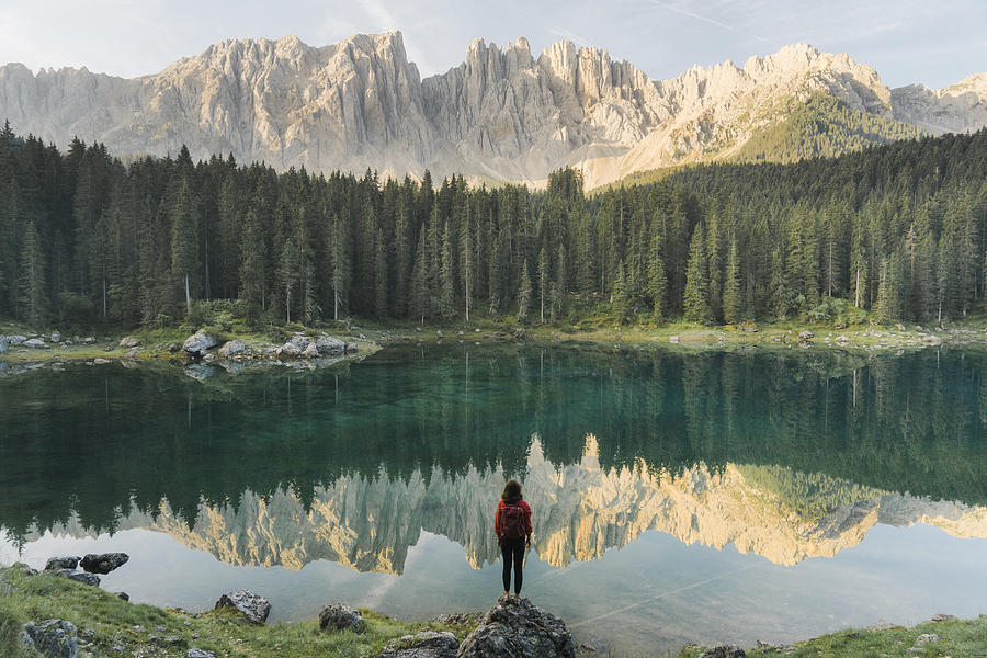 Woman standing and looking at  Lago di Carezza in Dolomites Photograph by Oleh_Slobodeniuk