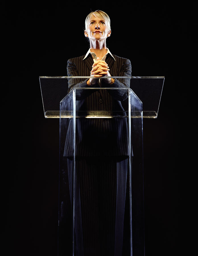 Woman standing at podium, hands clasped, low angle view Photograph by Ryan McVay