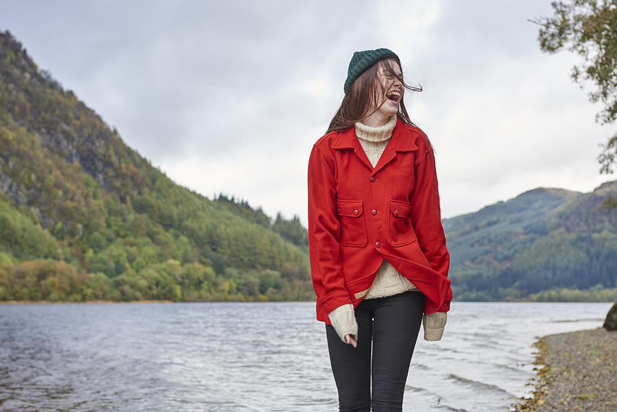 Woman standing by the side of a loch Photograph by Plume Creative