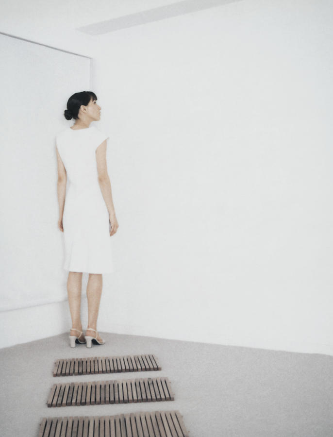 Woman standing in corner of room at end of path of wooden rectangles Photograph by Matthieu Spohn