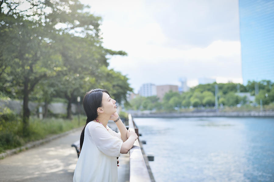 Woman standing in park along the river Photograph by Yagi Studio
