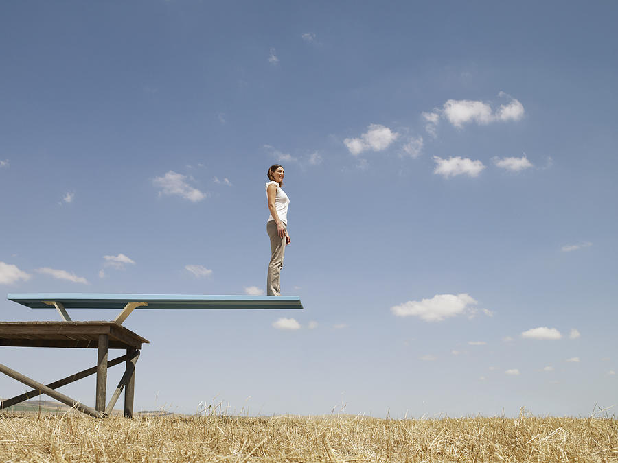 Woman standing on diving board in field Photograph by Martin Barraud