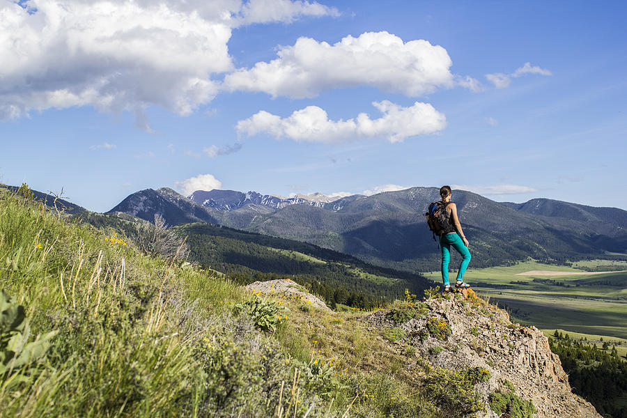 Woman stands on a rock looking out in the Rocky Mountains of Montana Photograph by Hannah Dewey