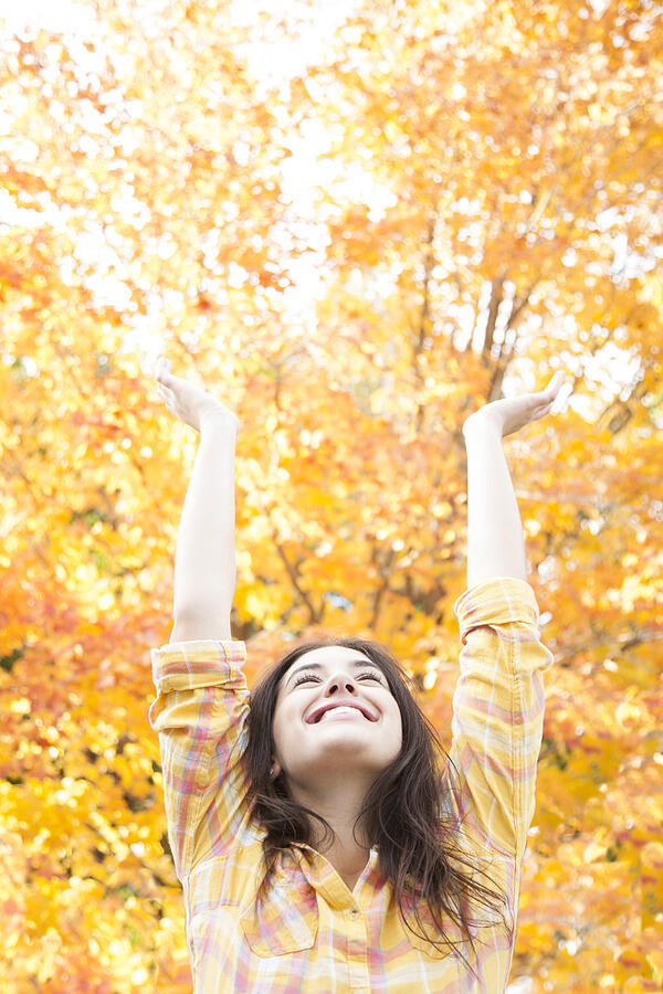Woman stretching arms up in front of Autumn tree Photograph by Jacqueline Veissid