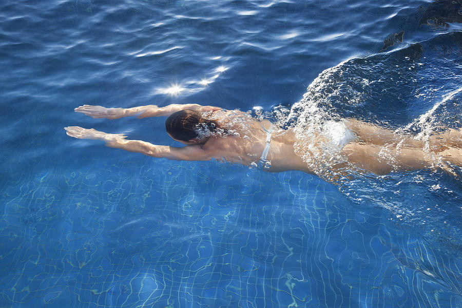 Woman swimming underwater in swimming pool Photograph by Philippe Bigard