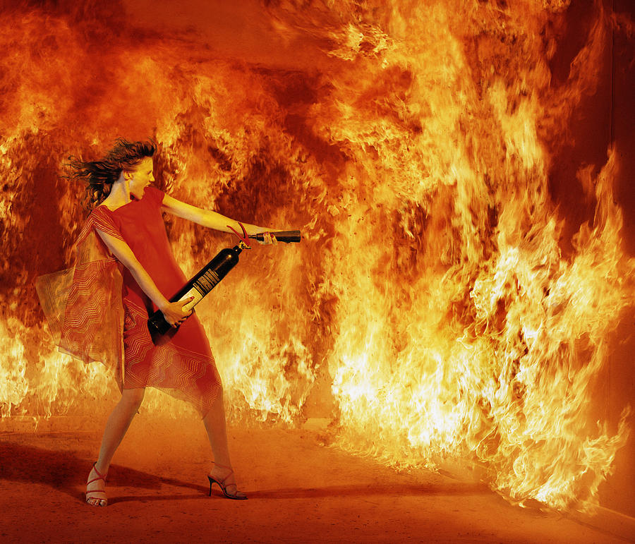 Woman tackling fire with hand held extinguisher (Digital Composite) Photograph by Martin Barraud