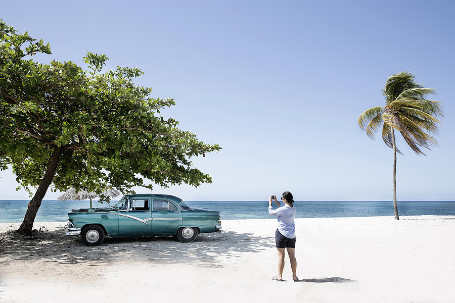 Woman takes photo of American car on the beach. Photograph by Gary John Norman