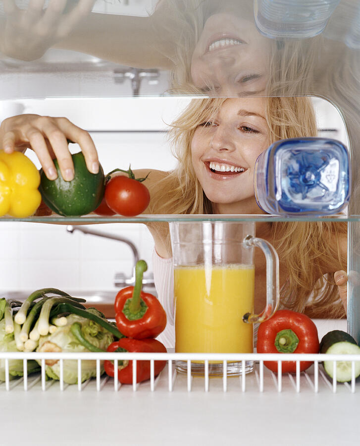 Woman Taking a Green Pepper from a Fridge Rack Photograph by Bill Ling
