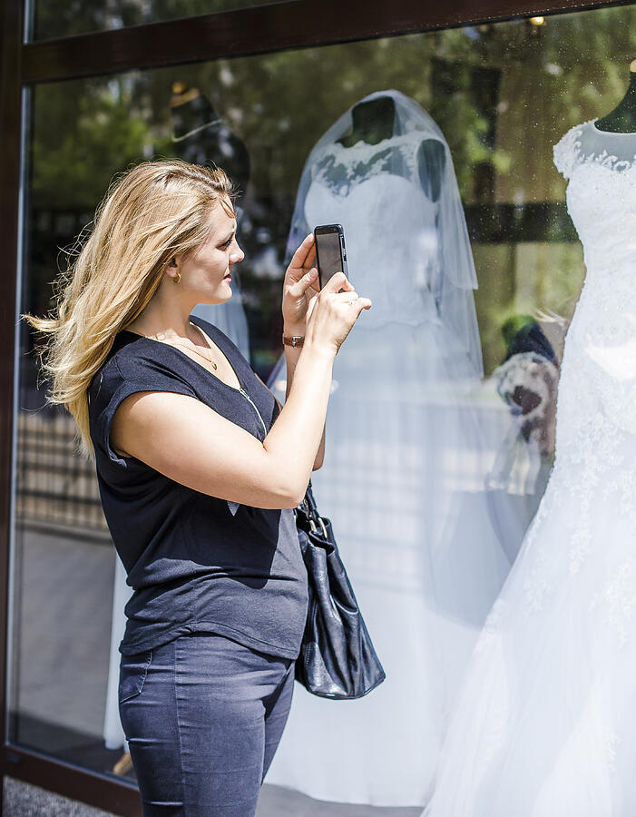 Woman taking a picture of a wedding dress Photograph by Maciej Frolow