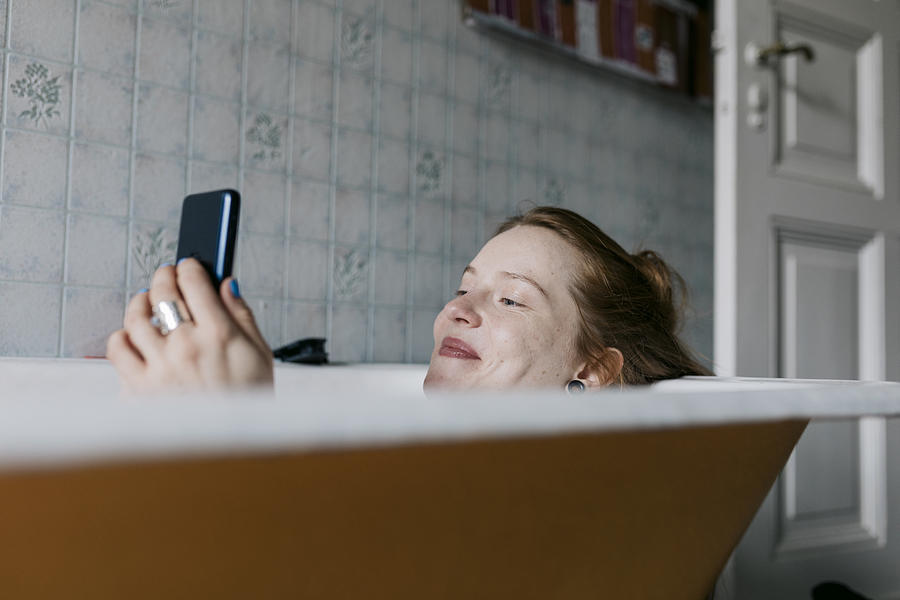 Woman Taking Bath And Smiling While Messaging Someone Photograph by Willie B. Thomas