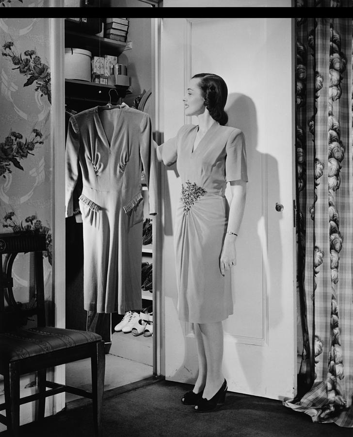 Woman taking dress from wardrobe, (B&W) Photograph by George Marks