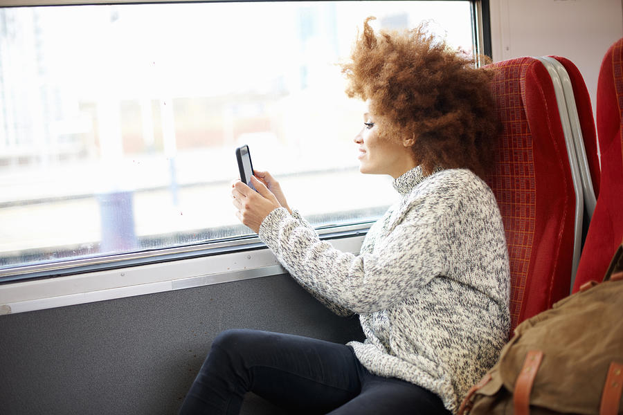 Woman taking photo with mobile phone from train, London Photograph by Peter Muller