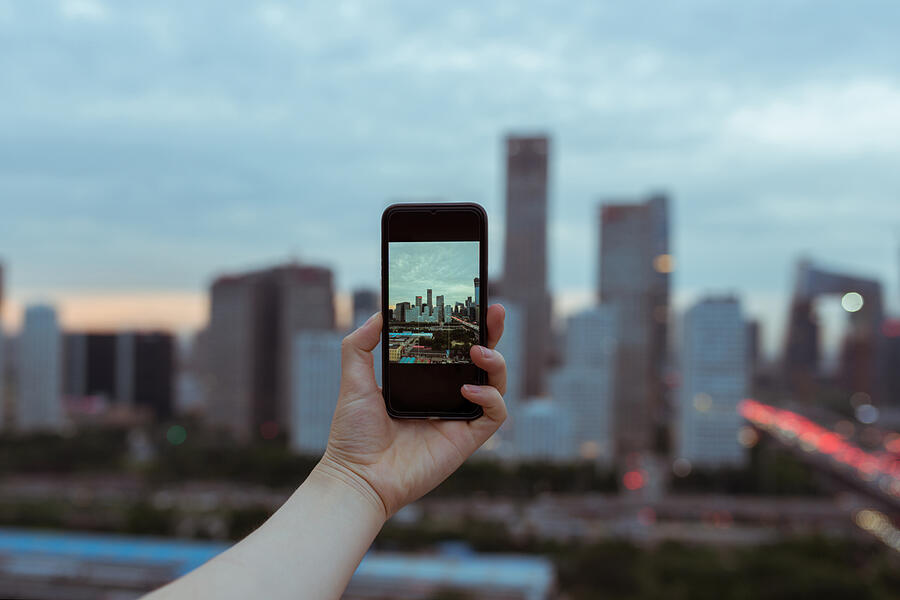 Woman taking pictures from personal point of view with smartphone of the Beijing Skyline Photograph by AerialPerspective Images