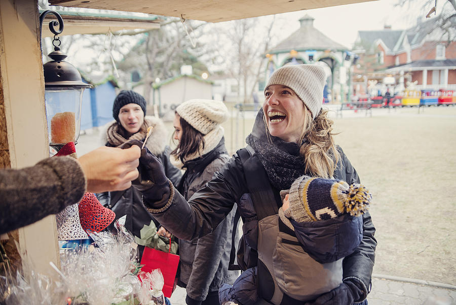 Woman tasting product at an outdoors public market in winter. Photograph by Martinedoucet