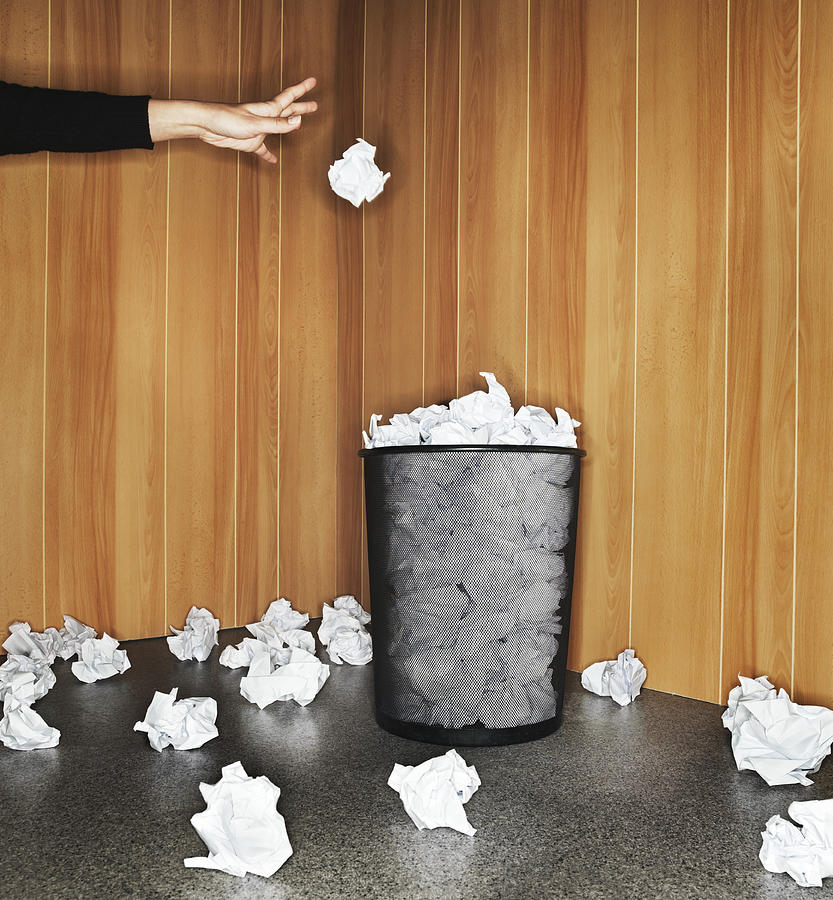 Woman throwing paper in waste paper bin, close-up of hand Photograph by Henrik Sorensen