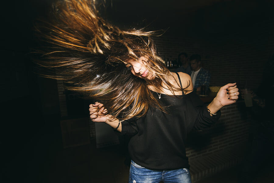 Woman tossing her hair and dancing in nightclub Photograph by Inuk Studio