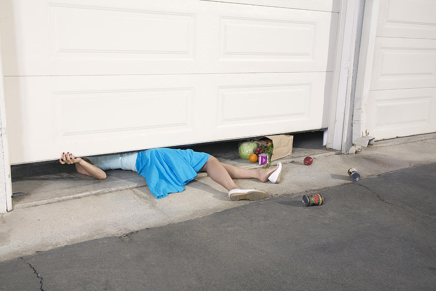 Woman trapped under garage door Photograph by Williams+Hirakawa