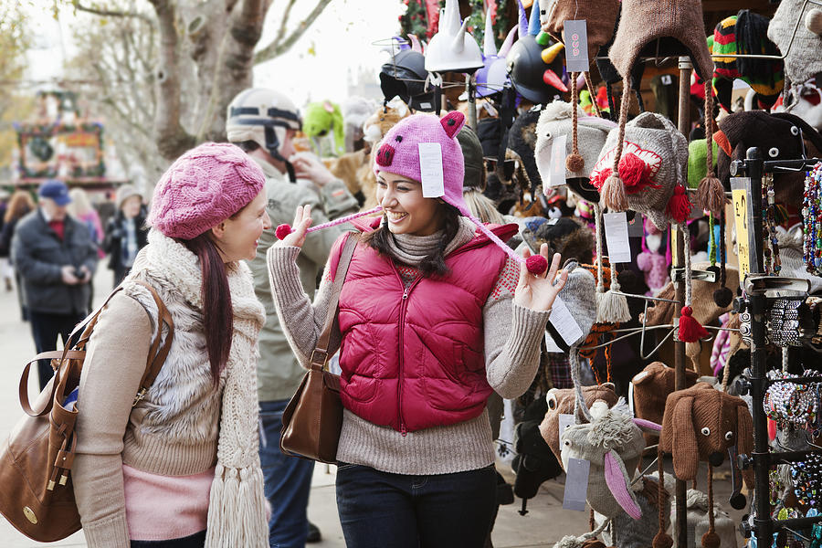Woman trying on hat with pigface at outdoor fair. Photograph by Betsie Van Der Meer
