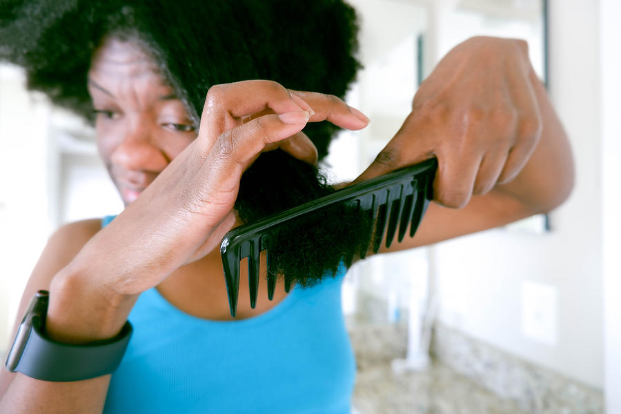 Woman Uses Wide-Tooth Comb to Detangle Wet Natural Hair Photograph by Grace Cary