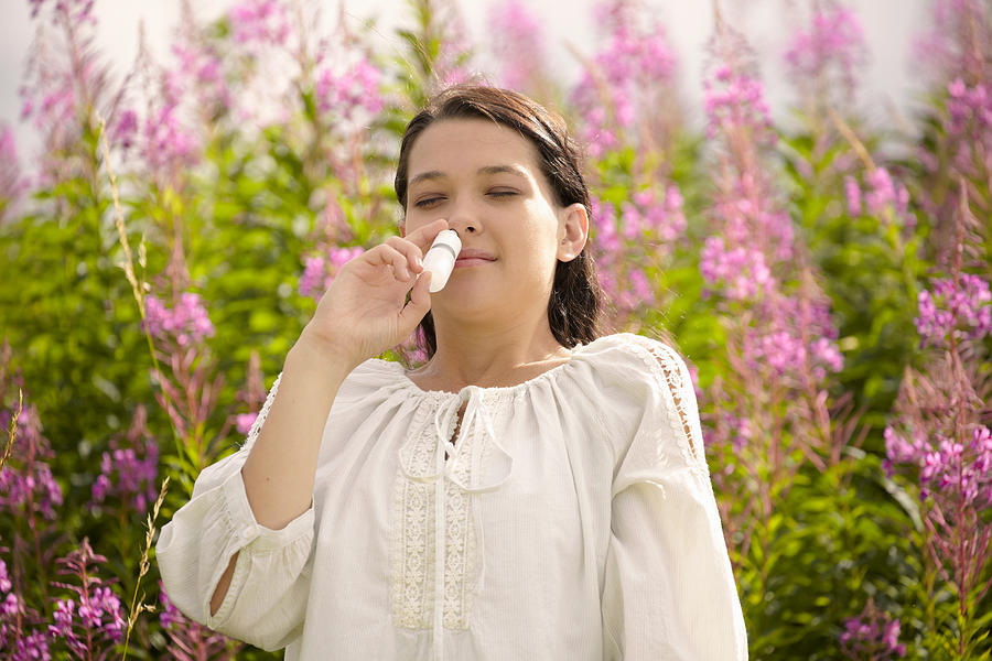 Woman using allergy relief nasal spray Photograph by Martin Leigh