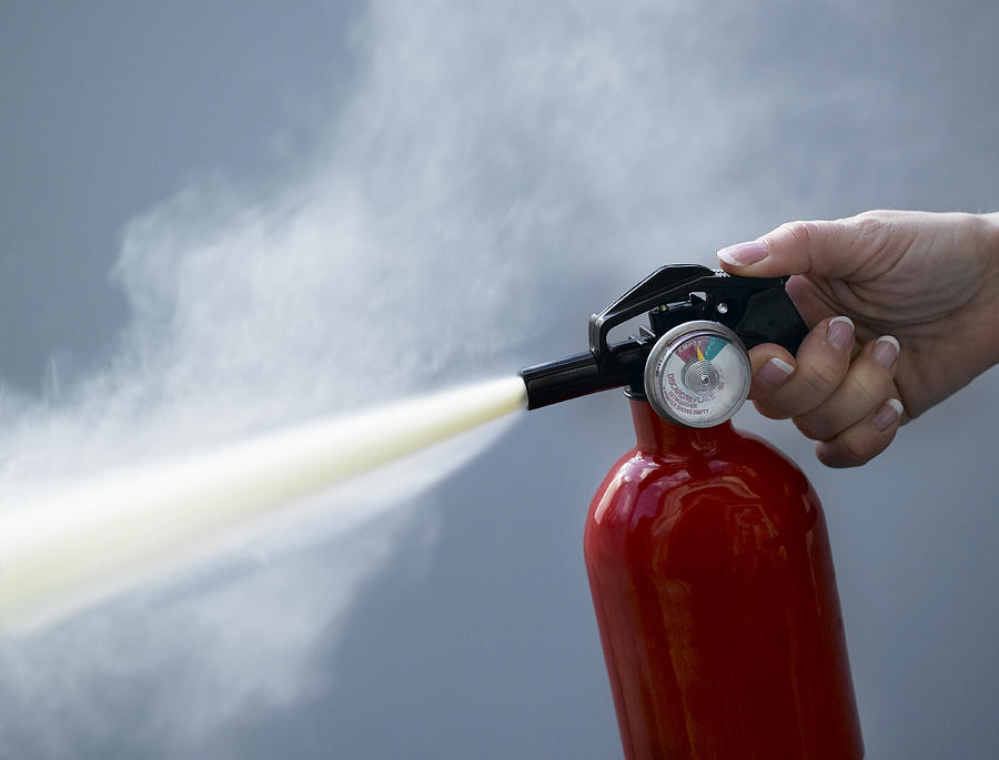 Woman using fire extinguisher, close-up Photograph by Jeffrey Coolidge