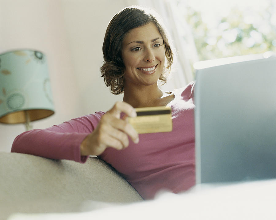 Woman Using Her Bank Card Online With a Laptop Photograph by Digital Vision.