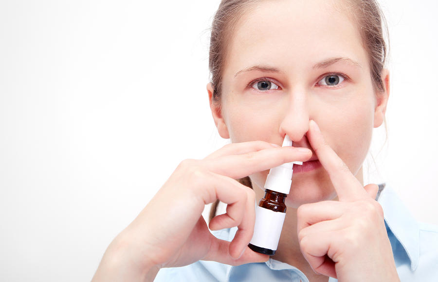 Woman using nasal spray and holding other nostril closed. Photograph by TommL