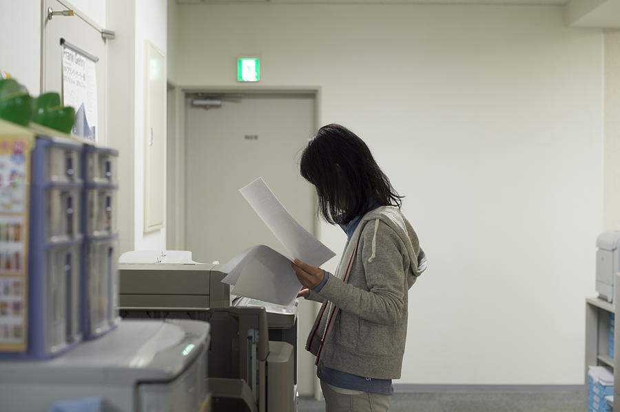 Woman using photocopier Photograph by Michael H