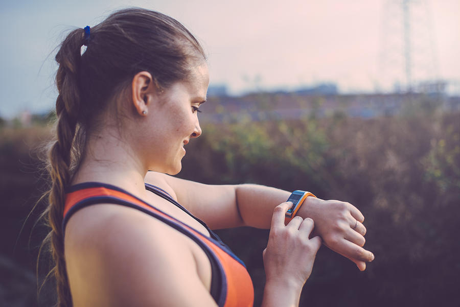 Woman using smartwatch outdoor. Photograph by Guido Mieth