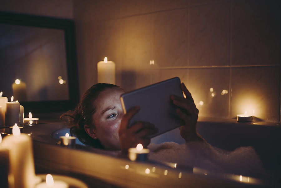 Woman using tablet pc in bathtub. Photograph by Guido Mieth